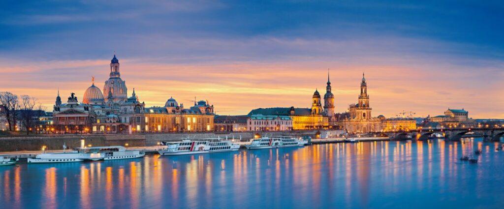 Die beleuchtete Altstadt von Dresden mit der Frauenkirche und der Elbe bei Sonnenuntergang – ein idealer Ort für ein stilvolles Dresden Escort Date.