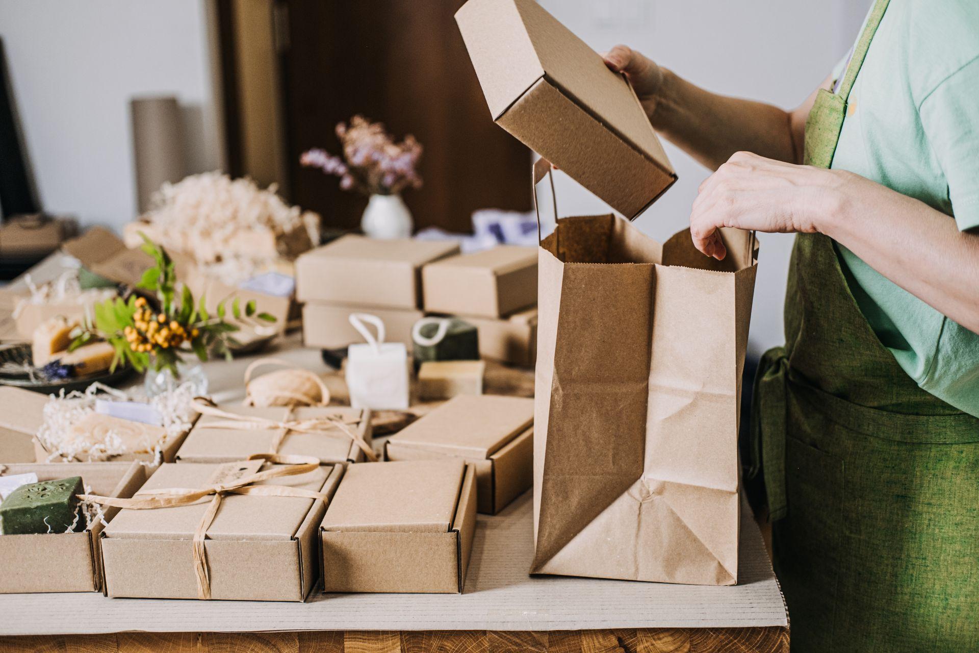 haende packen naturkartons in papiertuete mit nachhaltiger deko und umweltfreundlicher verpackung