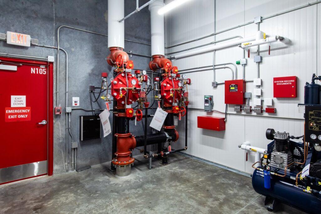 Ansicht eines Technikraums mit Ventilen, Leitungen und Pruefgeraeten im Rahmen einer Kontrolle durch Sachverstaendiger Loeschanlagen