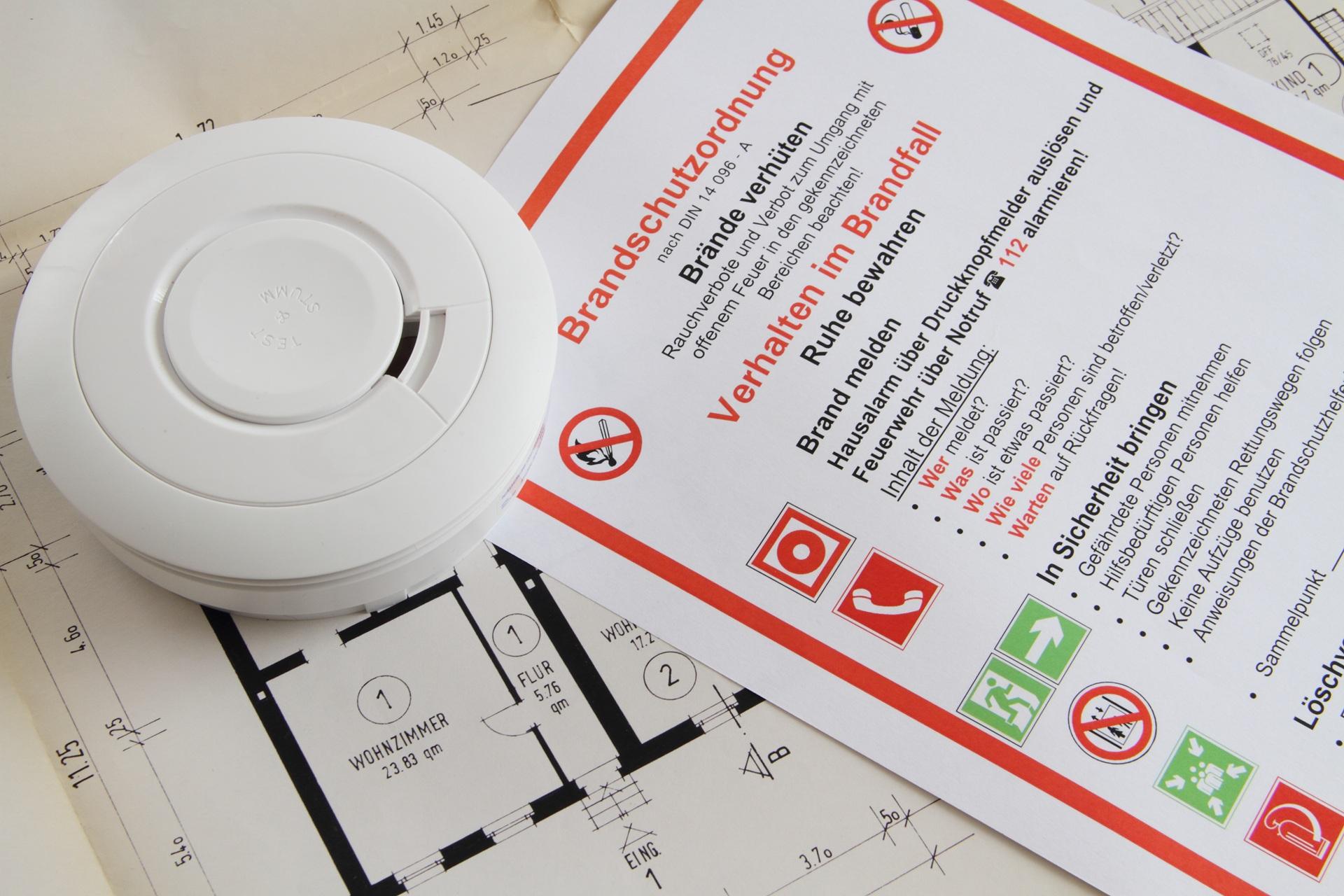 Rauchmelder liegt auf Brandschutzordnung und Bauplan | Brandwache Hamburg
